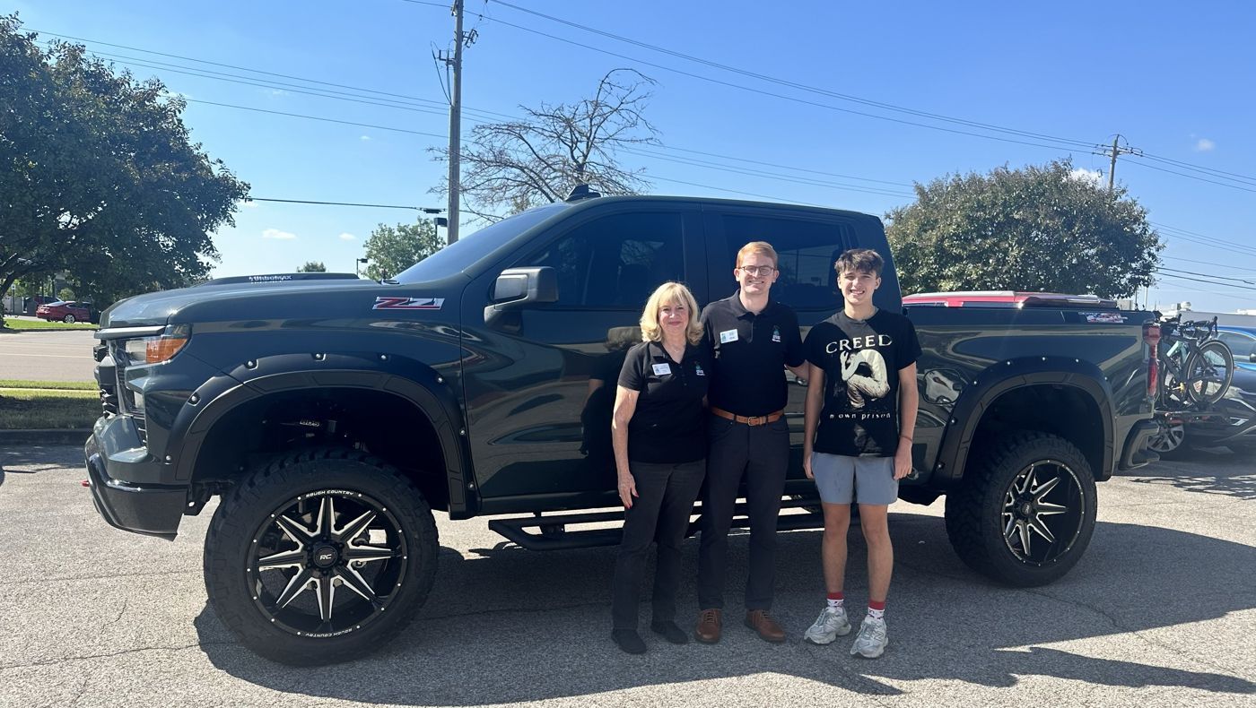 Knox standing by his lifted Z71 truck with Dream Factory volunteers